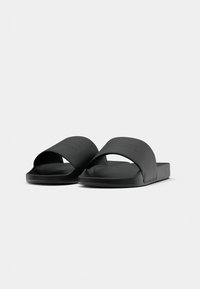 Pair of black slide sandals with wide textured straps and cushioned footbeds, shown against a plain light gray background.