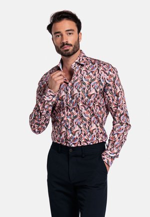 Langsleeve shirt met een kleurrijk bladerenpatroon in roze, blauw en bruin. Heeft een kraag, knopen en een slanke pasvorm. Gemaakt in combinatie met donkere broeken.