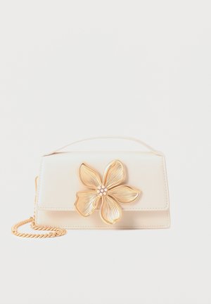 Cream rectangular handbag with top handle, gold chain strap, and large gold flower with pearl center on front flap.