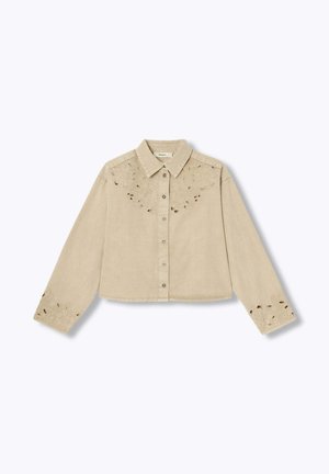 Chemise beige à manches longues avec col et boutons, ornée de broderies florales ajourées sur la poitrine et les poignets, posée à plat sur un fond blanc.
