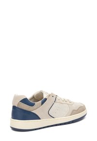 Baskets en suède beige avec des accents en cuir bleu, bout rond, détails perforés et semelle intermédiaire blanche à surface texturée.