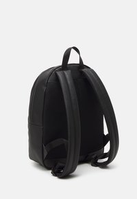 Mochila negra con correas de hombro acolchadas, panel trasero de malla y asa superior sobre un fondo blanco.