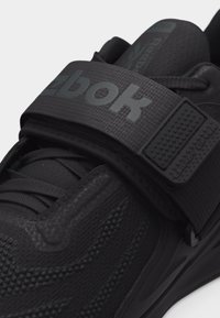 Μαύρο αθλητικό παπούτσι Reebok με υφαντό επάνω μέρος με υφή, κορδόνια και φαρδιά ρυθμιζόμενη λουρίδα με την ένδειξη "Legacy Lifter".