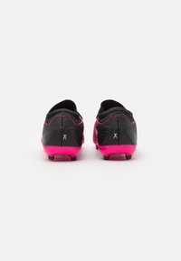Scarpe da calcio nere e rosa con tomaia testurizzata, suola rosa e dettagli posteriori. Design a profilo basso con cuciture nere.