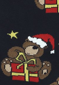 Wydziergany wzór brązowego misia, który ma na sobie czerwoną czapkę Mikołaja, trzymającego czerwony pudełko z prezentami przewiązane żółtą wstążką na ciemnym tle.