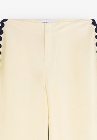 Yellow pants featuring a smooth texture and scalloped navy accents along the sides. The design includes a straight cut and front zipper closure.