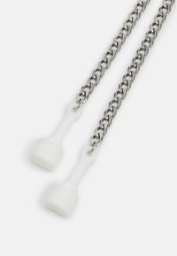 Deux chaînes en argent avec des poignées en silicone blanc pour maintenir des lunettes ou des masques faciaux sur un fond blanc.