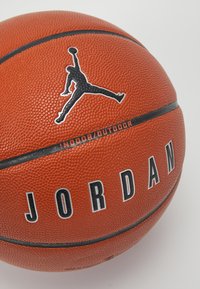 Oranje basketbal met een gematteerd oppervlak, voorzien van zwarte "JORDAN" letters en een Jumpman-logo. Ontworpen voor gebruik binnen en buiten.