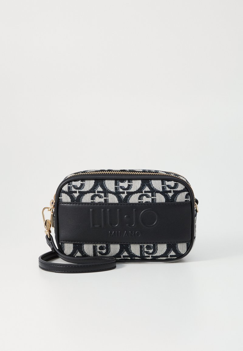 Taske i sort-hvidt mønster lavet af stof med glat sort læderdetalje, gylden lynlås og aftagelig rem. Dimensionerne er kompakte og rektangulære.