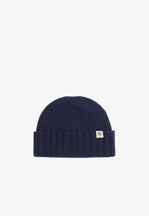 Marineblaue gerippte Strickmütze mit umgeschlagenem Bündchen und kleinem beigefarbenem Etikett mit symmetrischem Logo.