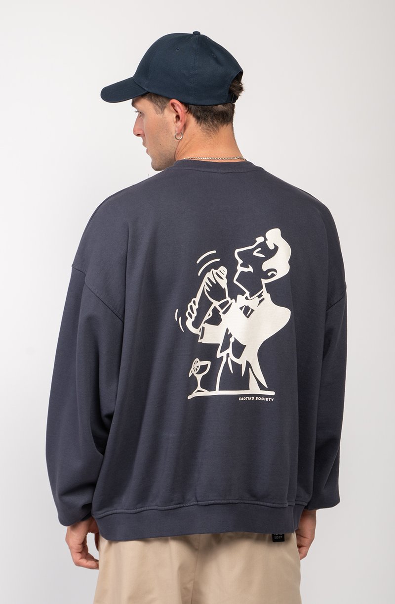 Sudadera de un azul marino oscuro con corte holgado y mangas largas. Presenta un gráfico blanco en la parte posterior de una persona agitando un cóctel.