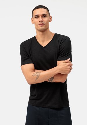 Zwarte, kortslip V-hals t-shirt van een zachte stof met een ontspannen pasvorm. Bevat een naaddetail langs de halslijn en de mouwen.