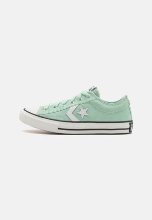 Light green canvas sneaker with a white star logo, rubber toe cap, and black stripe along the sole. Six eyelets and a low-top design.