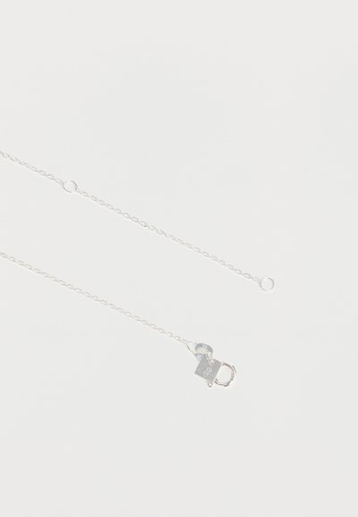 Collier à chaîne fine en argent avec un petit fermoir mousqueton et des anneaux d'extension sur fond blanc.