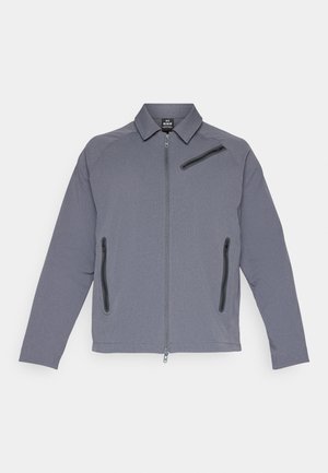 Sivi zip-up jakna s ovratnikom, koja ima dva bočna džepa i jedan džep na prsima, izrađena od teksturirane tkanine s glatkom završnom obradom.