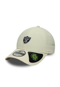 Gorra de béisbol beige con el logo de los Raiders bordado en la parte delantera. Presenta una visera curvada y una correa trasera ajustable. Textura suave.