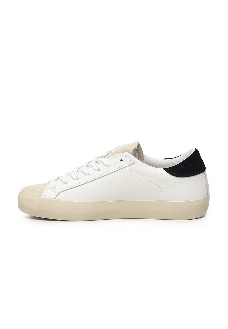 Witte leren sneakers met een suède neus, een platte crèmekleurige zool en een zwarte accent aan de hiel. Voorzien van een klassieke vetersluiting.