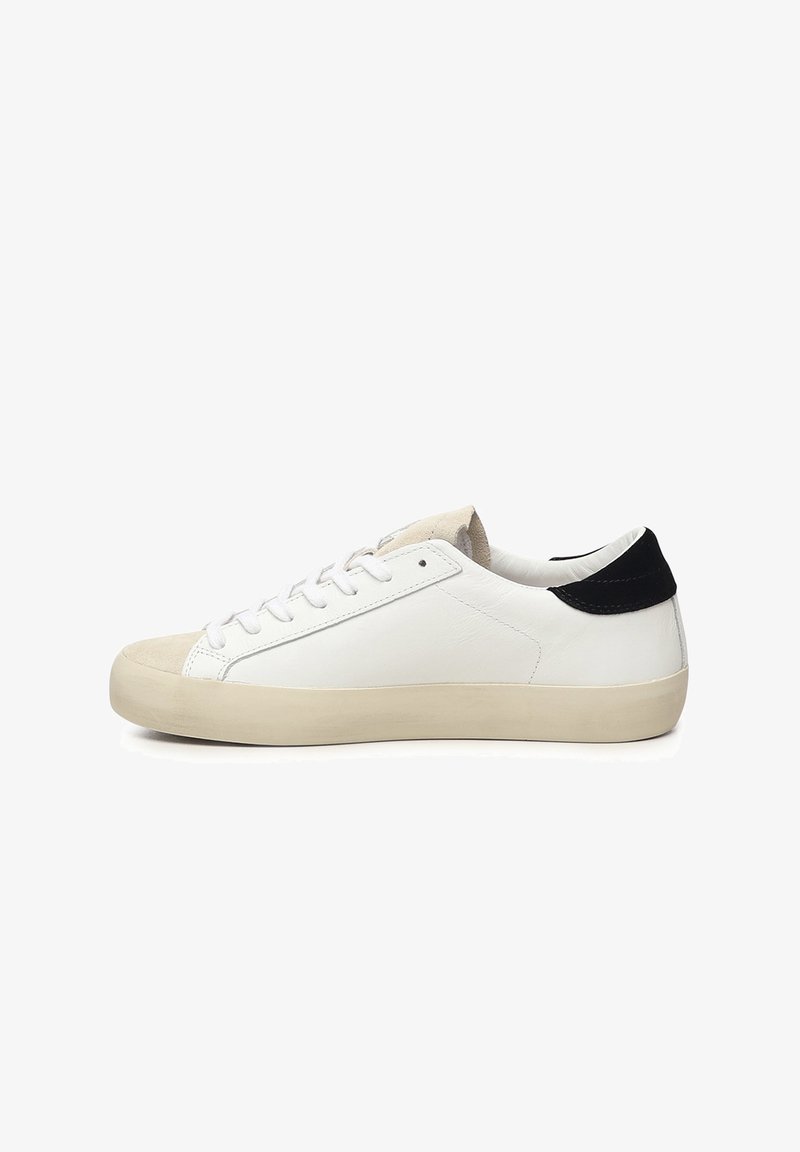 Zapatillas de cuero blanco con una punta de ante, suela plana color crema y un acento negro en el talón. Presentan un diseño clásico de cordones.