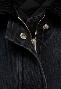 Black denim jacket featuring a corduroy collar, silver zipper, and snap fasteners, with a quilted inner lining for added texture.