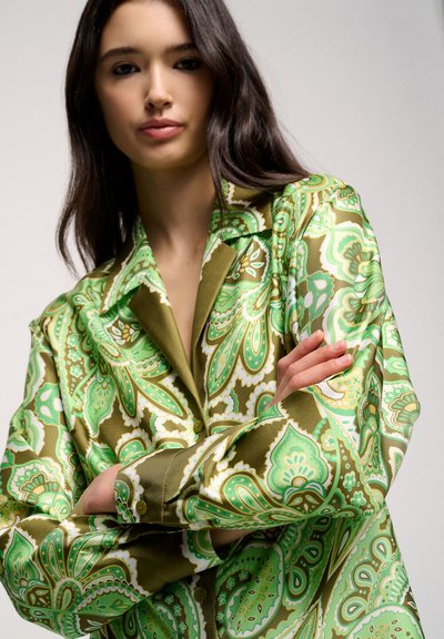 Chemise à manches longues avec un motif paisley vert et marron, présentant une texture satinée, un col pointu et des poignets à boutons.