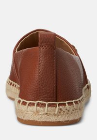Brown leather slip-on shoe with a textured finish, espadrille sole, and woven jute trim. Features a back tab for easier wear.