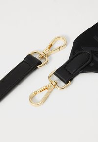 Sangle en cuir noir avec quincaillerie en métal doré, dotée de crochets à pression et d'une finition texturée. Les points forts du design incluent des accents lisses et cousus.