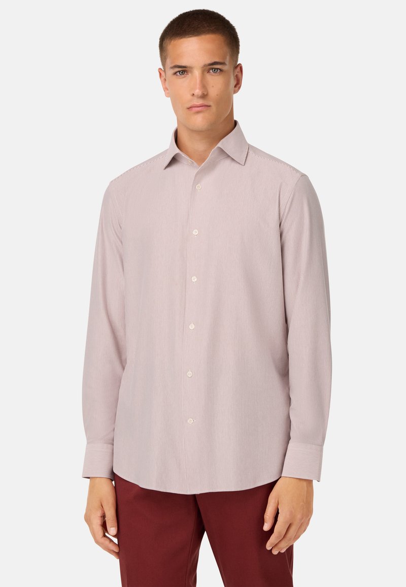 Una camicia a maniche lunghe di colore rosa chiaro con un sottile motivo a righe, colletto classico e orlo arrotondato, abbinata a pantaloni bordeaux scuri.