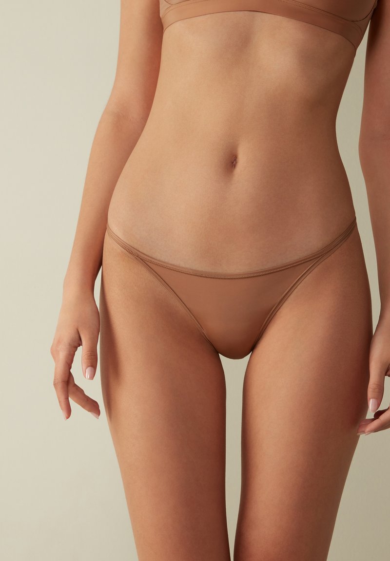 Tan sömlösa bikiniunderdelar med låg midja, mjukt material och minimal täckning, med tunna elastiska band i midjan och vid benen.