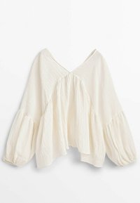 Blouse blanche ample avec un col en V, tissu texturé et manches bouffantes. Présente un design superposé et une belle retombée.