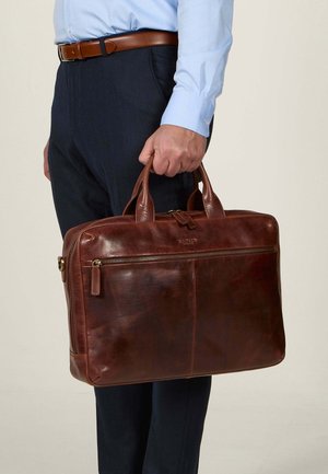 Brown leather briefcase with dual handles, zip closure, and exterior pocket. Textured surface and subtle branding on the front.