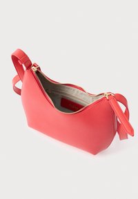 Τσάντα από δέρμα με υφή κοραλλιού, με χρυστό φερμουάρ, οβάλ σχήμα, ανοιχτό σχέδιο που αποκαλύπτει εσωτερικό σε ανοιχτό χρώμα, και λουράκι προσαρτημένο για μεταφορά.