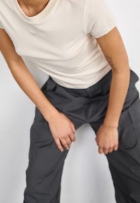 Krämfärgad t-shirt med kort ärm i kombination med lösa, mörkgrå cargobyxor med sidofickor, slät tyg och elastisk midja.