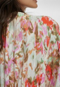Kimono floral multicolor, realizat dintr-un material moale și ușor, în nuanțe pastelate de roz, verde, portocalie și maro, cu o croială lejeră și un design deschis.