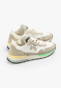 Beżowo-białe sneakersy z teksturowaną siateczką, zamszowymi akcentami, logo czaszki oraz wielokolorową gumową podeszwą z zielonymi i żółtymi detalami.