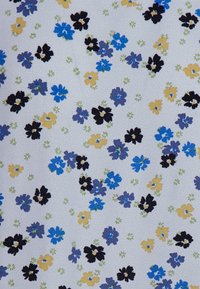Tecido branco adornado com um padrão floral disperso, apresentando flores azuis, roxas, pretas e amarelas, com acentos verdes e um fundo texturizado.