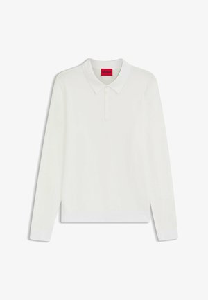 Polo a maniche lunghe bianco con una texture morbida, colletto abbottonato e polsini a costine. Presenta un'etichetta rossa con il marchio all'interno del girocollo.
