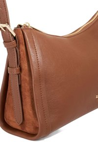 Bruine leren en suede handtas met een gebogen vorm, gouden rits en verstelbare schouderband, met gladde en gestructureerde oppervlakken.