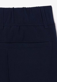 Donkerblauwe broeken met een gestructureerde tailleband en een vlakke achterzak. Voorzien van gestikte accenten en een elastische taille voor comfort en pasvorm.