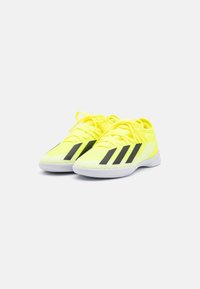 Scarpe da ginnastica gialle brillanti con strisce diagonali nere. Presentano una tomaia testurizzata, una suola ammortizzata e lacci gialli coordinati.