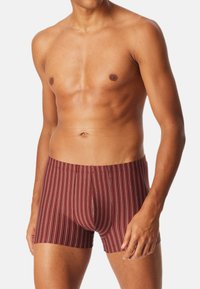 Rød og hvid stribet boxershorts med en tætsiddende pasform, der har en blød tekstur og elastisk talje, vist på en model.
