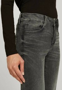 Slim-fit grå denimjeans med en urtvättad look, fem fickor och svarta detaljer. Synlig sömnad och lätt slitage vid låret.