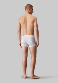 Fehér pamut boxer alsónadrág, Calvin Klein logós derékszíjjal, testhez simuló fazonnal és sima textúrával. A modell hátulról látható.