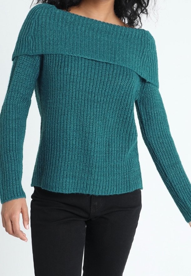 Pull turquoise en maille à épaules dénudées avec texture côtelée, manches longues et ourlet droit, associé à un pantalon noir.