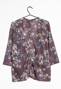 Blouse florale avec un fond bordeaux, offrant une coupe ample, un col rond, des manches trois-quarts et une texture subtile.