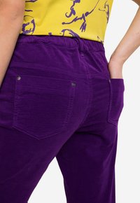 Lila kordfläskbyxor med en texturerad yta, med bakfickor och resårmidja för komfort.