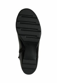 Semelle de chaussure en cuir noir avec une texture, un motif antidérapant et des rainures profondes, ainsi qu'un bord arrondi. Détail de zip sur la partie supérieure.