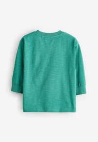 Camisa verde de manga larga con puños y cuello acanalados vista desde atrás sobre fondo blanco.
