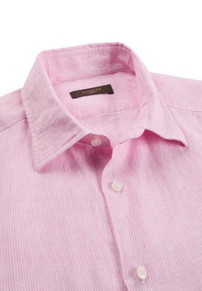 Camicia rosa chiaro con bottoni e sottili righe verticali bianche, con collo classico, stesa in piano mostrando i bottoni superiori e l'etichetta.