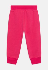 Ružové flísové tepláky s rebrovaným pásom a manžetami. Hladká textúra s elastickým materiálom pre pohodlie. Jednoduchý dizajn, bez vzorov.