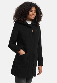 Black fleece coat with a hood, front button closure, two large pockets, and tan accent hardware detail. Soft texture, mid-length design.